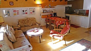 Una sala de estar acogedora con sofá, mesa de comedor y una zona de cocina con refrigerador y fregadero.