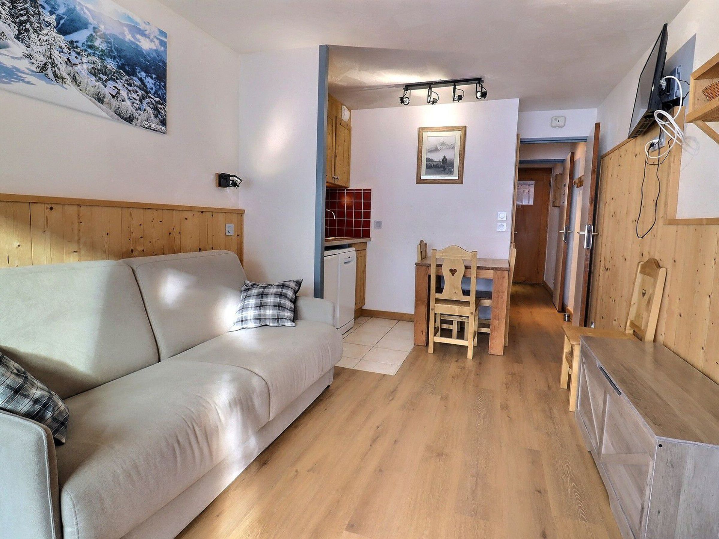 Una habitación acogedora con sofá, mesa de madera para comer y zona de cocina.