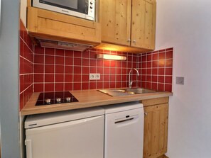 A compact kitchen with a built-in microwave, a sink, and a dishwasher. - Charming Studio on Slopes, Pets Welcome, Near Shops (Méribel)