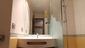 A bathroom with a sink, mirror, shower, and a door leading to another room. - Charming Studio on Slopes, Pets Welcome, Near Shops (Méribel)