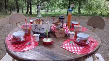 Montaje de picnic con una mesa de madera, individuales de lunares rojos y diversos alimentos y bebidas.