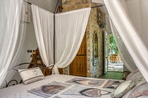 A bedroom with a canopy bed, a wooden ladder, and a view of an outdoor area with a wooden table and chairs. - The Bastidon of the Angel (Méounes-lès-Montrieux)
