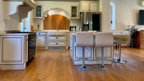 A modern kitchen with a central island, stainless steel appliances, and a bar area with stools.