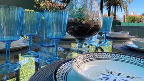 A table set with blue glassware and plates, surrounded by palm trees and a clear sky.