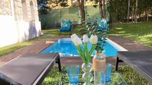 A glass-top table with a vase of white tulips, a glass bottle, and blue glasses.