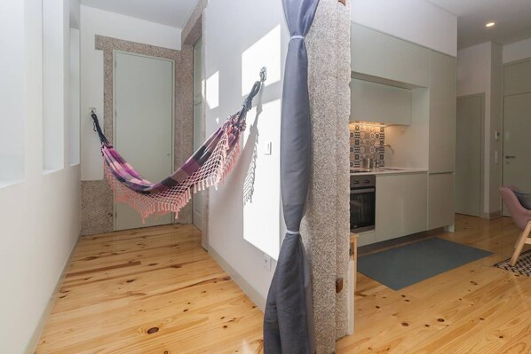A modern apartment with a hammock, a kitchen, and a dining area.