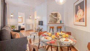 Un salon moderne avec une table à manger en verre, des sièges confortables et un grand tableau accroché au mur.