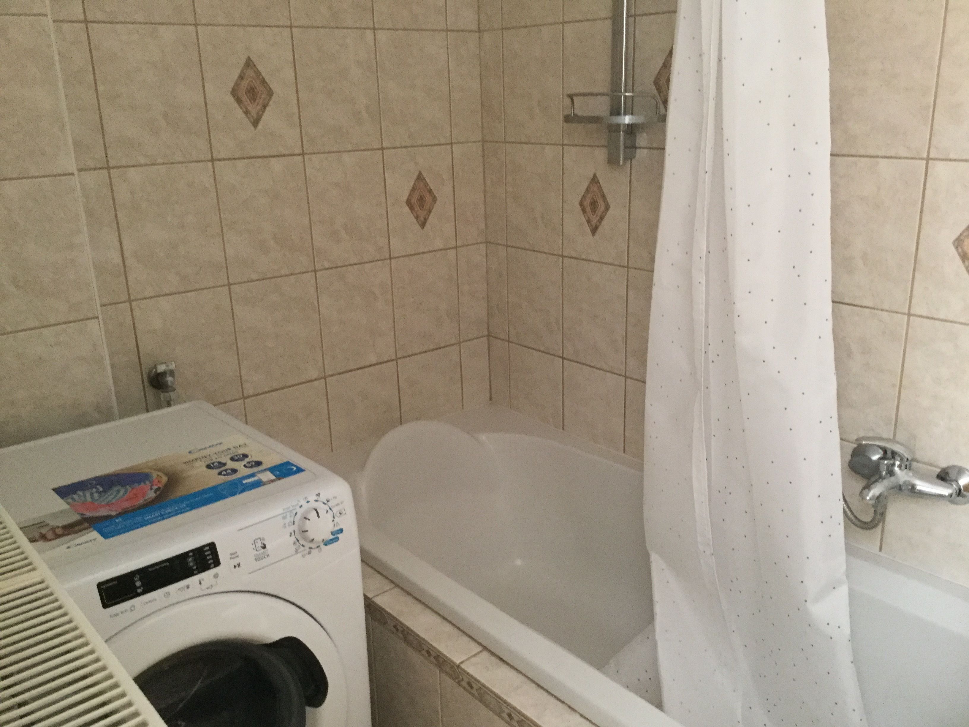Une salle de bain équipée d’un lave-linge, d’une baignoire et d’une douche.