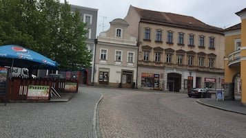 A cobblestone street with buildings, a pizzeria, and a car parked on the side.