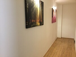 Un pasillo con suelo de madera y dos cuadros en la pared.