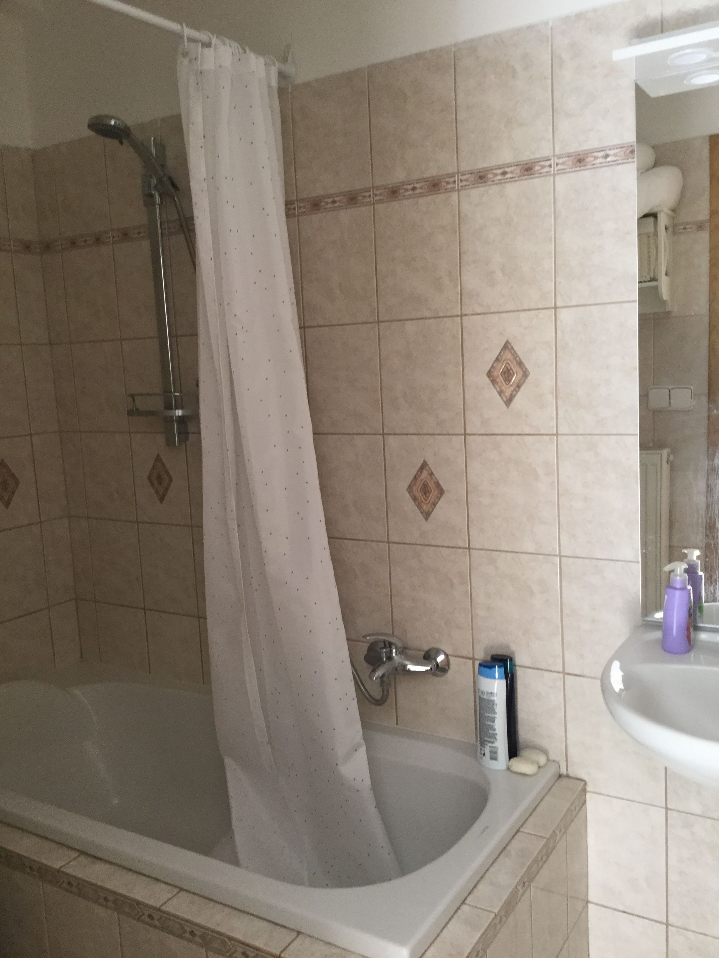Et badeværelse med badekar, bruser og vask.