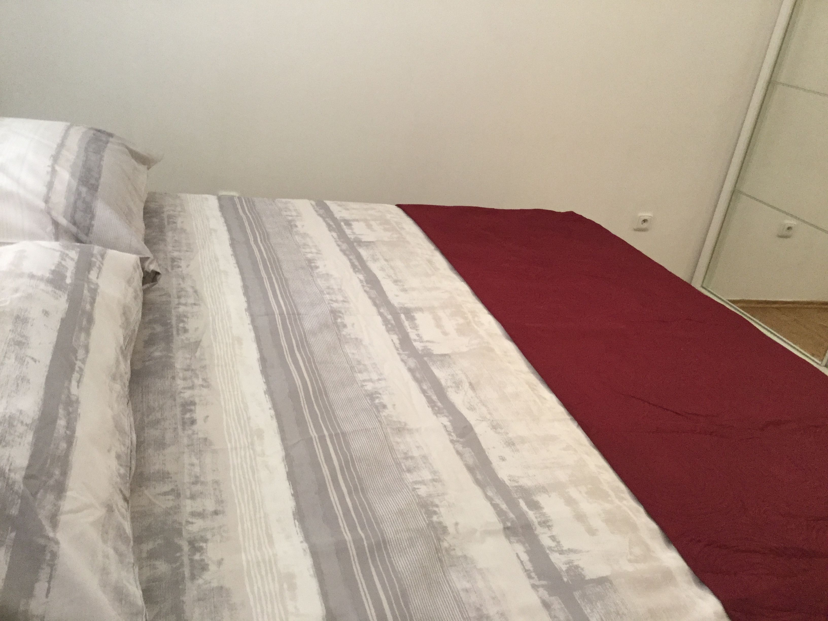 Un lit avec une couvre-lit à rayures et une couverture rouge.