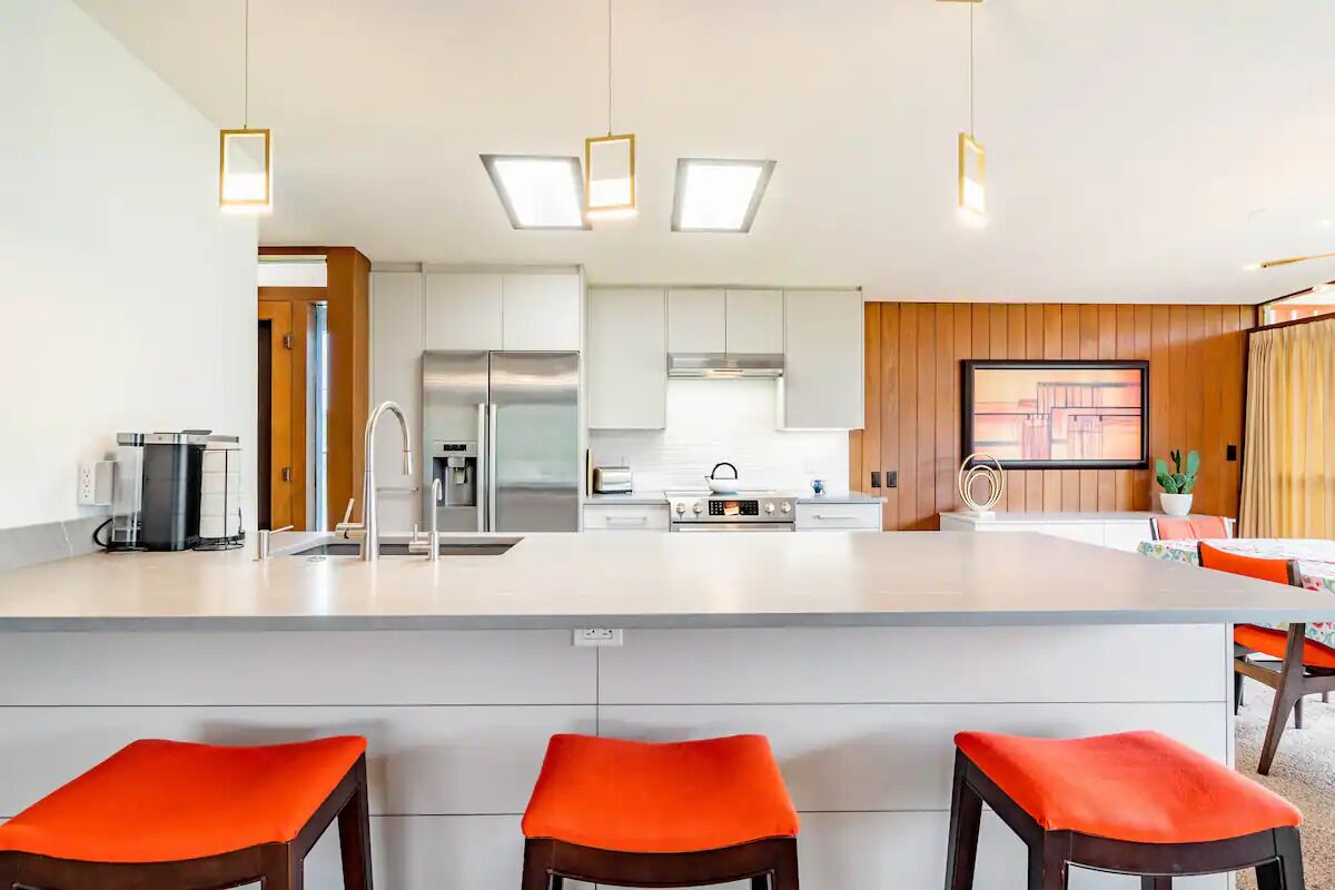 A modern kitchen with a central island, stainless steel appliances, and bright pendant lighting.