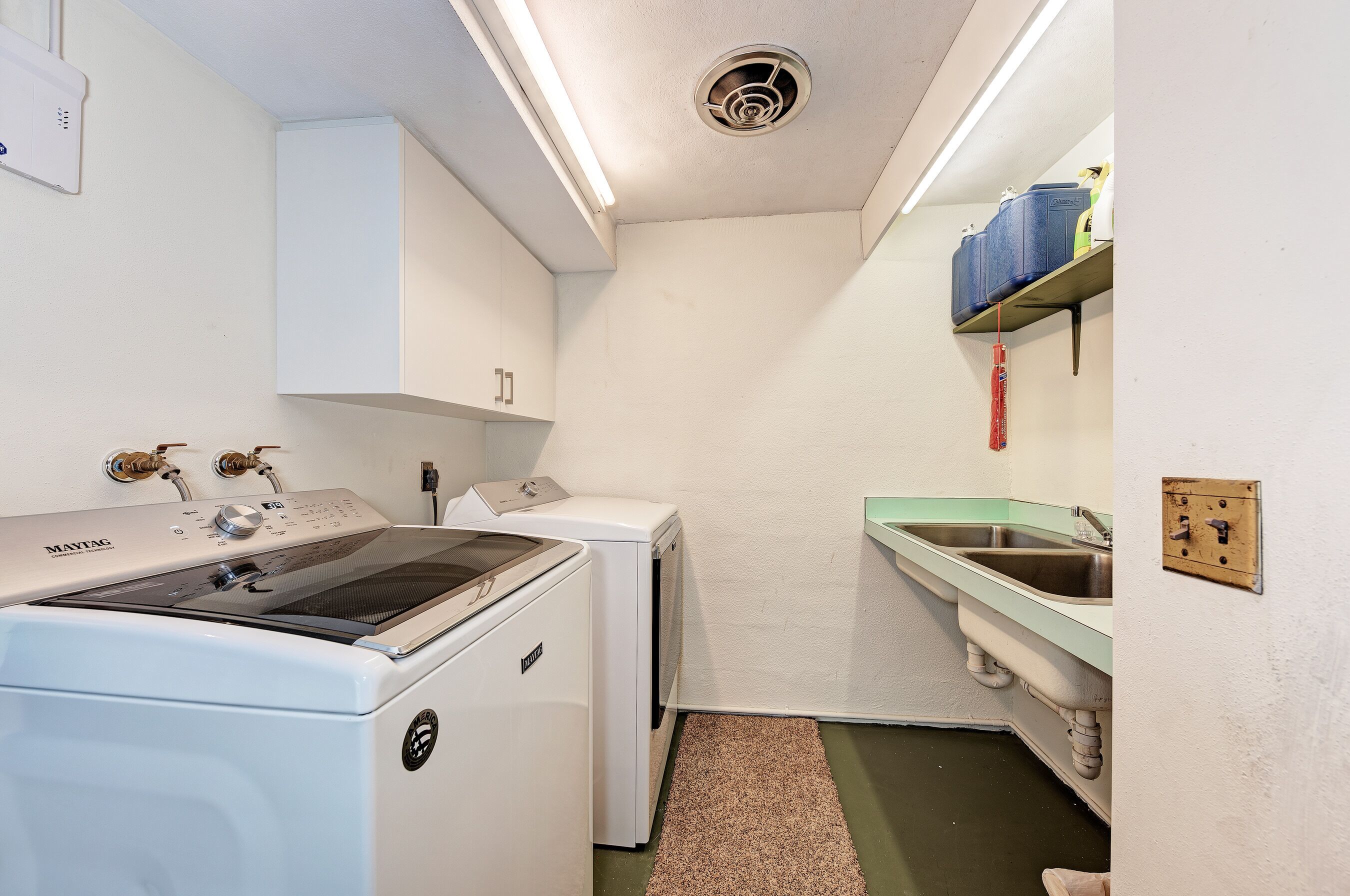 A laundry room with a Maytag washer, a dryer, and a sink.