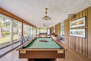 Relax by the pool table in this spacious room with a view of the outdoors through glass doors.