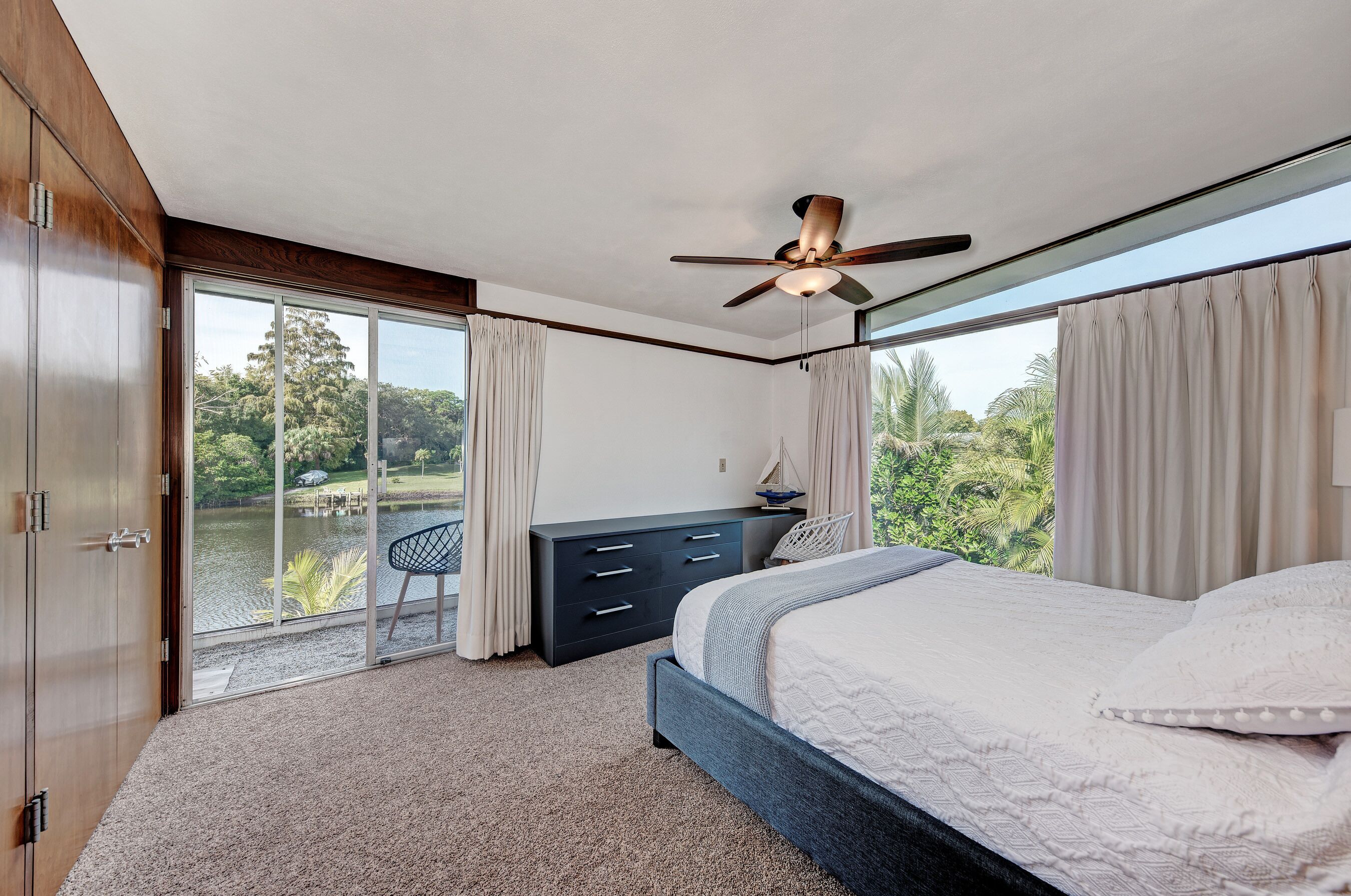 A bedroom with a bed, a desk, and a view of a lake.