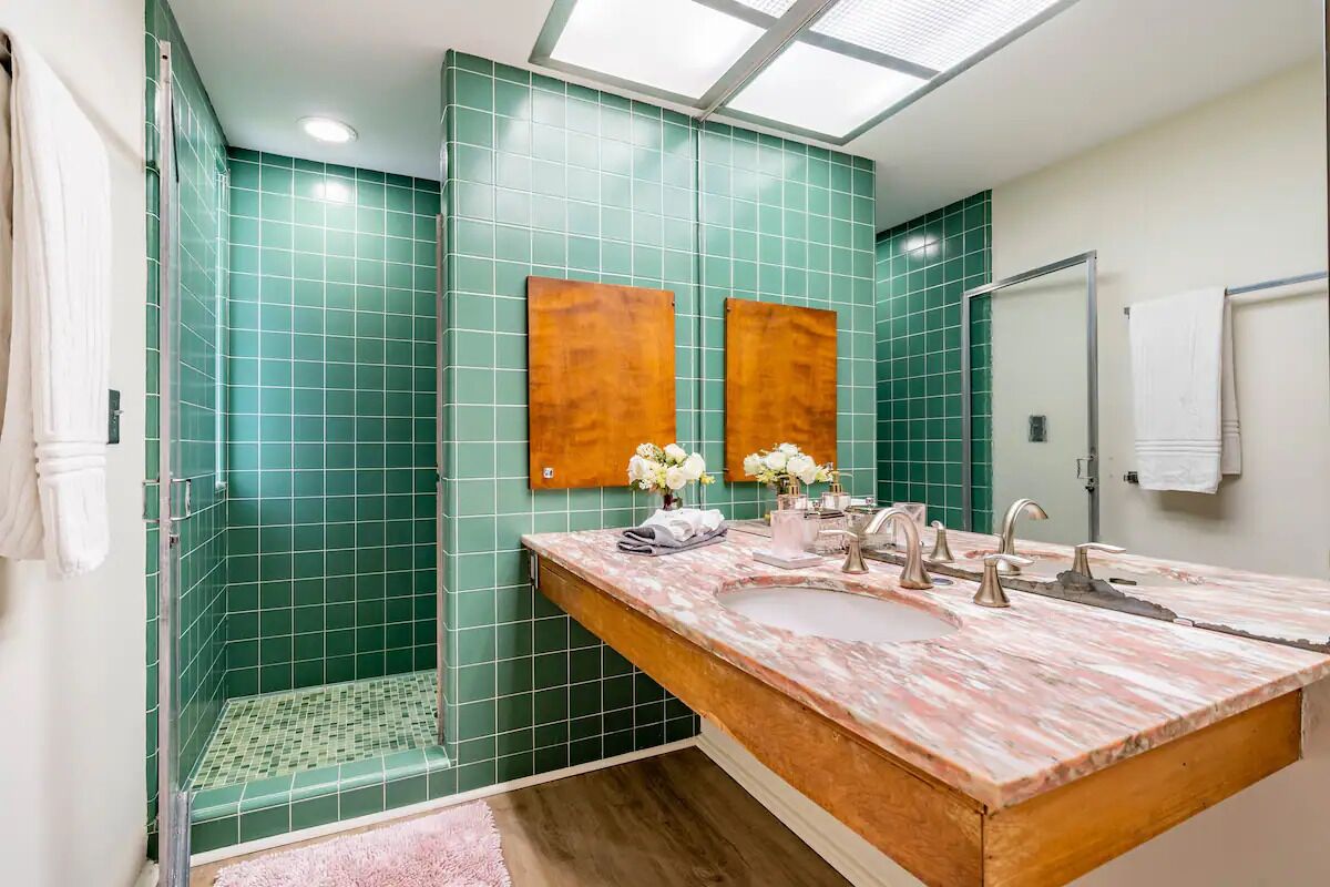 A bathroom with a large sink, two mirrors, and a shower area.