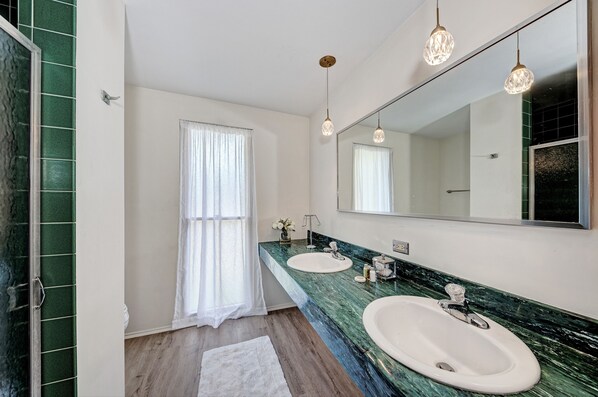 A bathroom with two sinks, a large mirror, and hanging pendant lights.