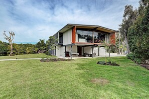 A modern two-story house with a large glass window, a covered patio, and a well-maintained lawn. - 4 bed 3 bath Waterfront Home by Ralph Twitchell (Sarasota)
