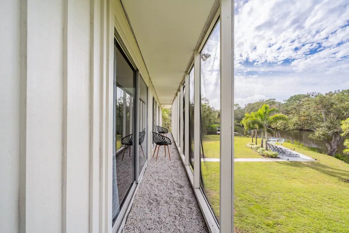 A corridor with large windows, a gravel path, and outdoor seating.