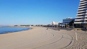 Een strand met een kronkelend pad dat naar een gebouw leidt met meerdere balkons.