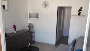 Een ruimtelijk ingerichte leefruimte met een kitchenette, een eethoek, een bank en een klein tafeltje.