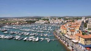 A marina with numerous boats docked, surrounded by buildings with Mediterranean architecture.