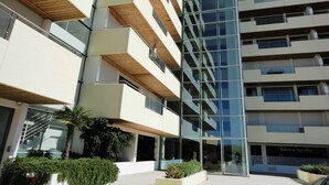 A modern multi-story building with balconies, large windows, and a clear sky.