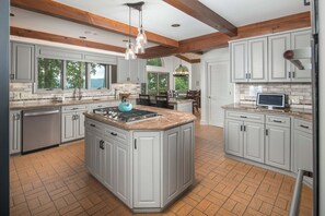 Una cocina amplia con una isla central, encimeras de granito y armarios blancos.