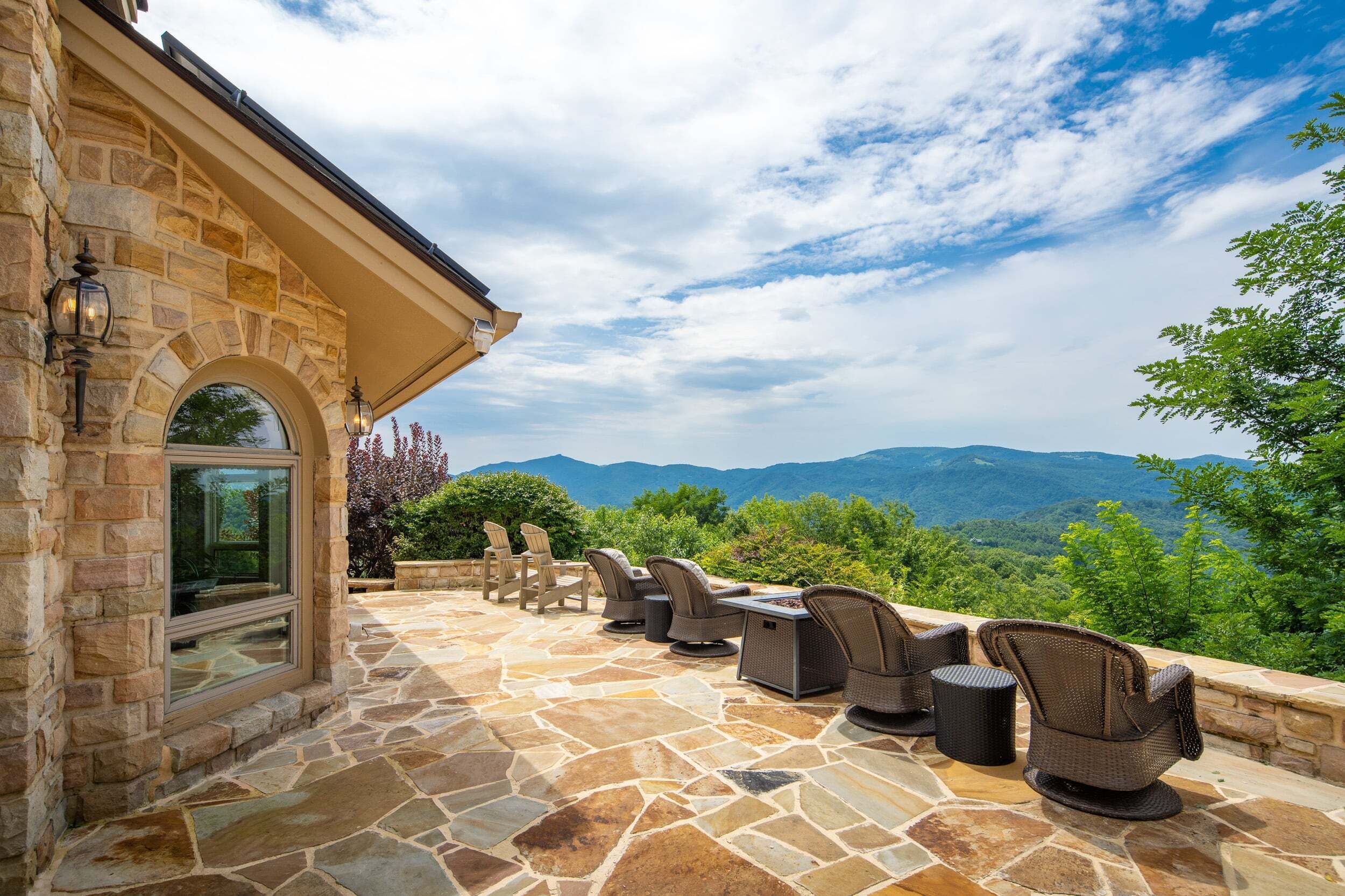 An outdoor patio with stone flooring, wicker furniture, and a view of mountains.