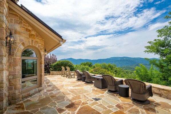 An outdoor patio with stone flooring, wicker furniture, and a view of mountains.