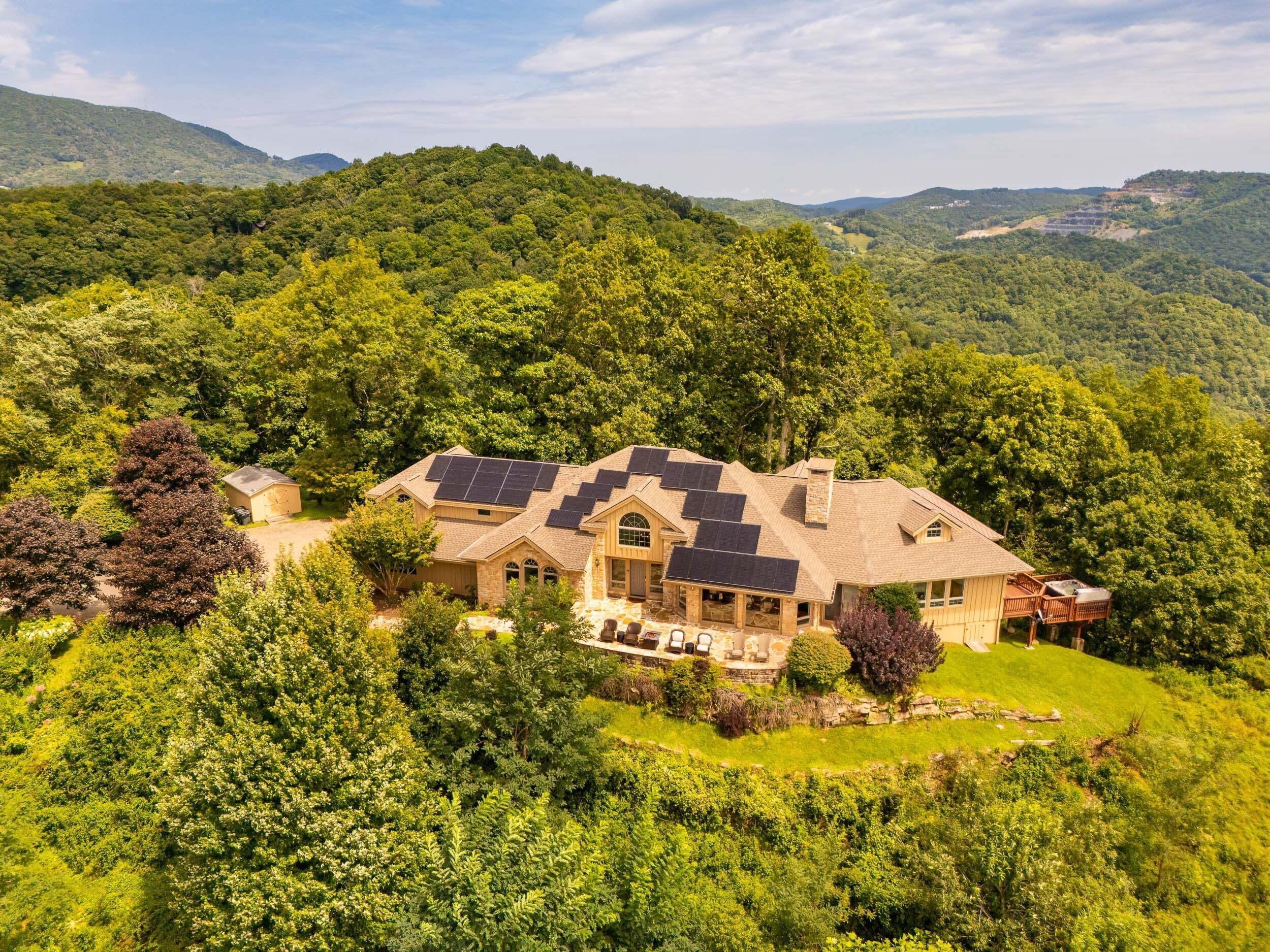 A house with a large roof area covered in solar panels, surrounded by lush greenery and hills.