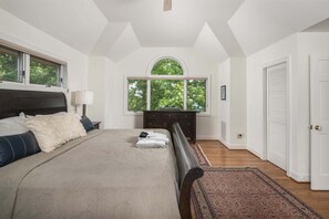 Un dormitorio con una cama grande, un aparador, una ventana y una puerta.