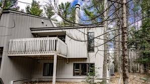 A two-story house with a balcony, surrounded by trees. - Harbor Cove #39 | Private Beach Access on Little Traverse | Pool | Fireplace (Harbor Springs)
