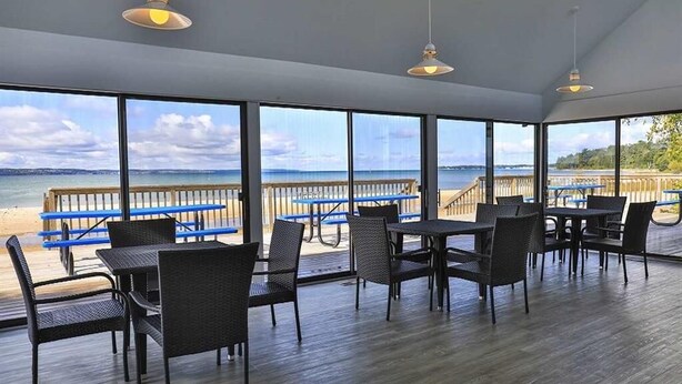 A spacious indoor area with large windows offering a view of the beach and ocean. - Harbor Cove #39 | Private Beach Access on Little Traverse | Pool | Fireplace (Harbor Springs)