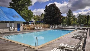 A swimming pool with lounge chairs and a wooden deck. - Harbor Cove #39 | Private Beach Access on Little Traverse | Pool | Fireplace (Harbor Springs)
