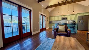 A spacious living room with a large sliding glass door leading to a balcony, a leather armchair, and a wooden coffee table.