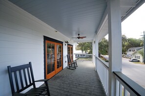 A porch with two rocking chairs, a ceiling fan, and a view of the street.