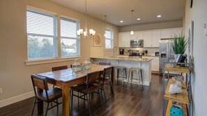 Una cocina moderna con una isla central, una mesa de comedor de madera y taburetes de bar.