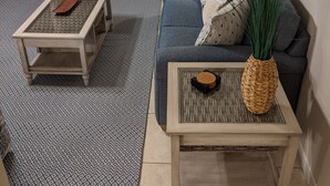 Una sala de estar con un sofá, dos mesas auxiliares, una lámpara y una planta decorativa.
