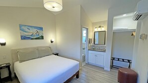 A bedroom with a bed, bedside tables, a painting, and a bathroom with a sink, mirror, and towel rack. - Private house with 3 suites. Modern, Clean & Comfortable! (Portland)