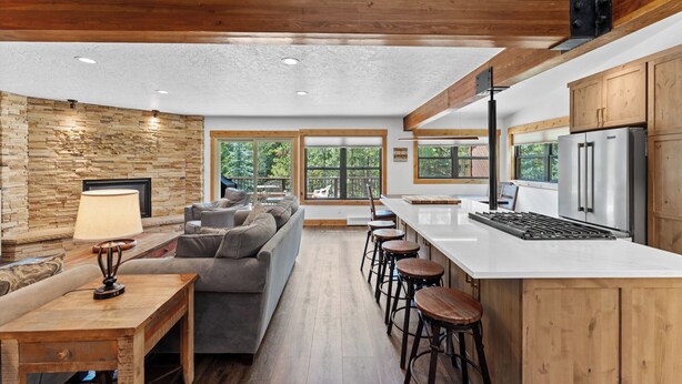 A modern kitchen with a large island, wooden cabinets, and a stone accent wall. - Private Sunken Outdoor Hot Tub, Near 3 Ski Resorts! (Frisco)