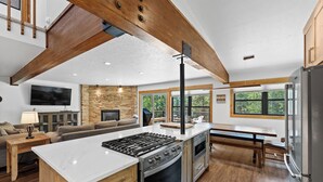 A modern kitchen with a large island, built-in oven, and a dining area with a bench. - Private Sunken Outdoor Hot Tub, Near 3 Ski Resorts! (Frisco)