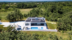 A modern house with a swimming pool, surrounded by lush greenery and hills in the background. - Villa**** SANIVARO with heated pool and SPA (Sanvincenti)