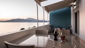 Un balcon avec une table en verre, des fauteuils en osier, une bouteille de champagne et un verre de champagne garni de fraises.