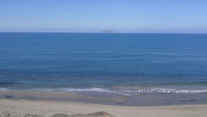 Une plage avec une eau d’un bleu limpide et une île qui se dessine à l’horizon.