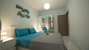 Une chambre à coucher avec un lit, des tables de chevet, un miroir et une porte.