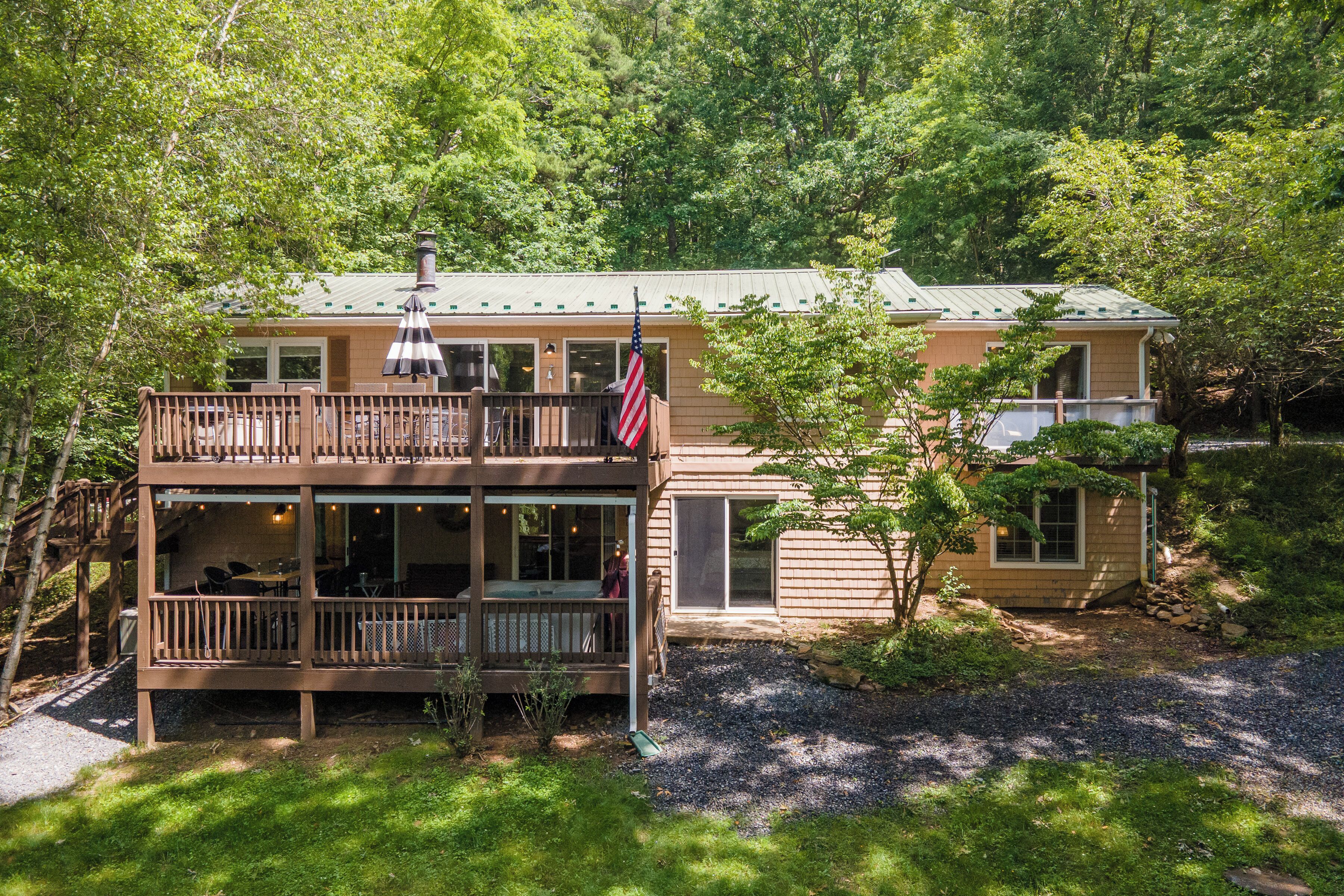A two-story house with a deck, a flag, and a chimney.