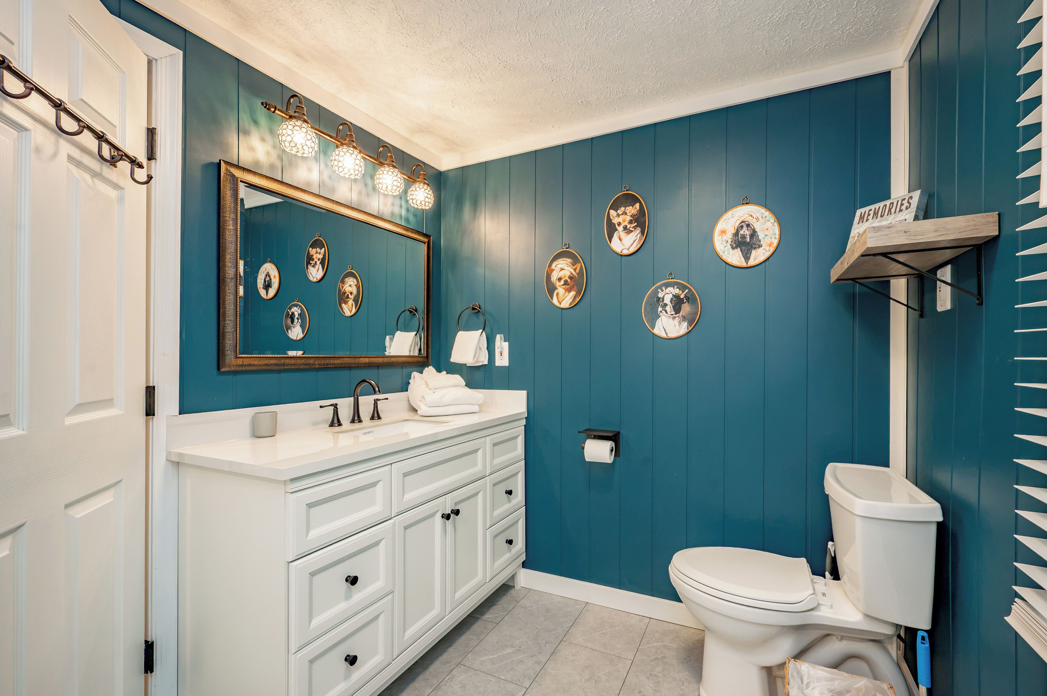 A bathroom with a white vanity, a large mirror, and a toilet.