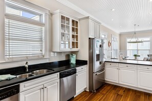 A kitchen with white cabinetry, stainless steel appliances, and a black countertop. - 2 Rooftop Decks | Downtown IOP | Pool | Elevator | 1 Blk From Beach | Pets (Isle of Palms)